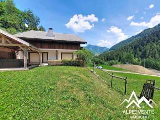 Nestled amidst breathtaking mountain scenery, this property offers a serene escape with its charming wooden-accented house and expansive green lawn.