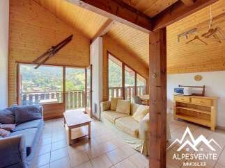 Experience mountain living in this charming chalet-style living room, featuring a vaulted wooden ceiling and large windows offering breathtaking valley views.