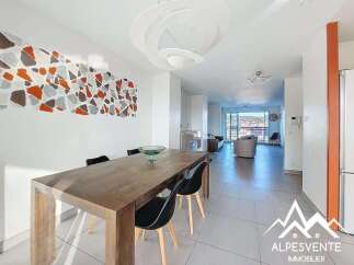 This spacious dining and living area features a modern wooden dining table with sleek black chairs, perfect for family meals.