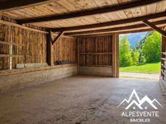 Discover this rustic wooden barn, offering a spacious interior with exposed beams and a concrete floor.