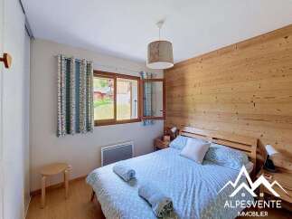 Experience cozy mountain living in this charming bedroom featuring a warm wooden accent wall and a comfortable bed adorned with patterned linens.