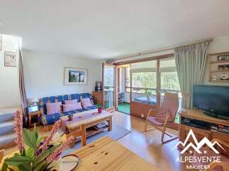 Discover this charming living room featuring a comfortable blue sofa with patterned cushions and a wooden coffee table.