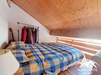 Cozy attic bedroom featuring a comfortable bed with a blue and yellow plaid comforter and matching pillows.