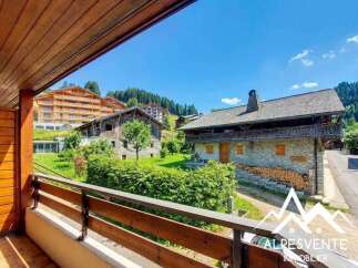 Experience the charm of alpine living with this stunning property, featuring traditional stone architecture and a picturesque wooden balcony overlooking lush greenery.