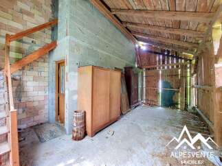 This unfinished interior space offers a unique opportunity for renovation, featuring exposed brick and concrete block walls, along with a rustic wooden ceiling.