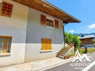 Charming alpine property featuring traditional wooden shutters and a welcoming stone staircase adorned with potted flowers.