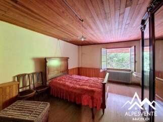 Step into this charming bedroom featuring a rustic wooden ceiling and walls, creating a warm and inviting atmosphere.
