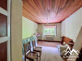 Discover this charming room featuring a rustic wooden ceiling and a large window offering picturesque views of the surrounding greenery.