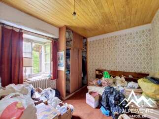 This charming room features a wooden slatted ceiling and patterned wallpaper, creating a cozy atmosphere.