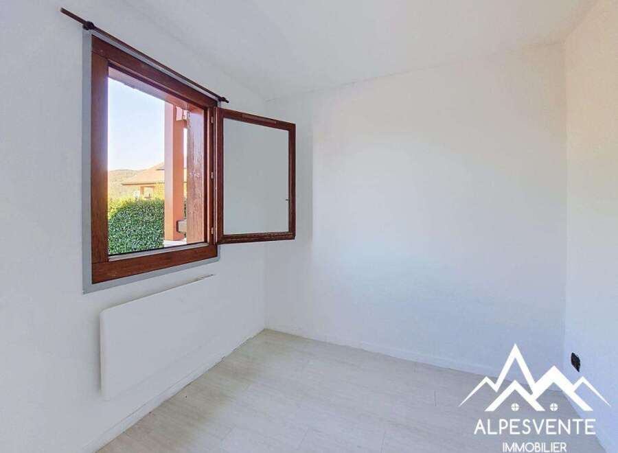 This bright and airy room features a large wooden-framed window offering scenic views of lush greenery and distant hills.