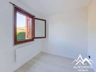 This bright and airy room features a large wooden-framed window offering scenic views of lush greenery and distant hills.