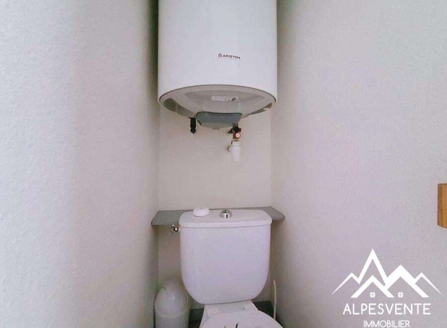 This compact bathroom features a white Ariston water heater mounted above a white toilet.