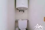 This compact bathroom features a white Ariston water heater mounted above a white toilet.