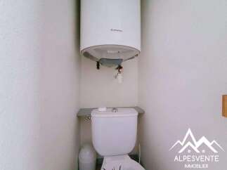 This compact bathroom features a white Ariston water heater mounted above a white toilet.