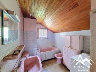 This charming bathroom features a pink bathtub, sink, and bidet, offering a unique retro aesthetic.