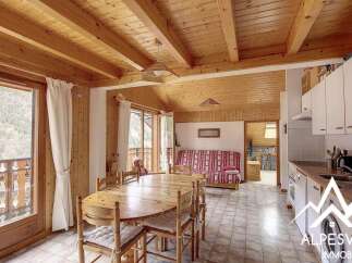 Experience cozy living in this charming mountain retreat, featuring a warm wooden interior with exposed beams and a spacious dining area perfect for family gatherings.
