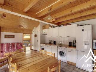 This charming alpine property features a cozy living area with a striped sofa and a rustic wooden dining table, perfect for family gatherings.