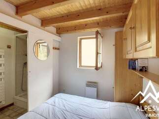 Discover this charming bedroom featuring a cozy bed, a modern shower room, and ample wooden cabinetry for storage.