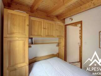 This charming bedroom features a built-in wooden wardrobe and shelving unit, offering ample storage and a cozy, integrated feel.