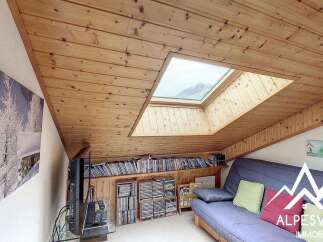 Discover this charming attic living space, featuring a cozy sofa and ample storage for your media collection.
