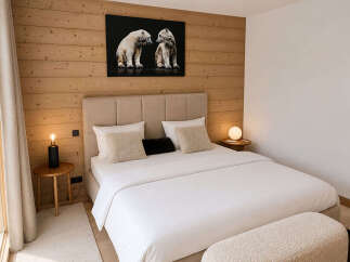 Experience cozy luxury in this beautifully appointed bedroom, featuring warm wood paneling and a striking polar bear artwork.