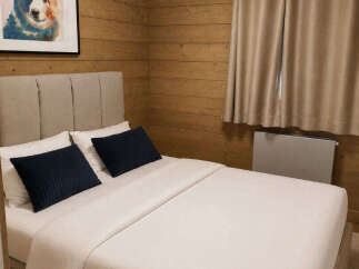 Experience cozy mountain living in this charming bedroom featuring warm wood-paneled walls and a comfortable bed adorned with plush pillows.