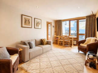Experience cozy mountain living in this charming apartment, featuring a comfortable sofa and plush rug perfect for relaxing after a day on the slopes.