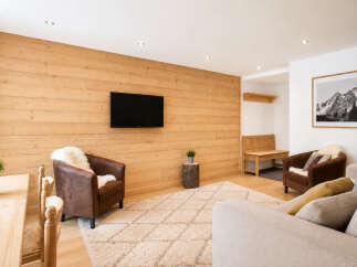 Experience cozy living in this charming room featuring a warm wooden accent wall and a modern flat-screen TV.