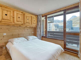 Experience cozy mountain living in this charming bedroom featuring rustic wooden paneling and charming heart-shaped details on the cabinetry.