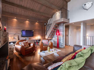 Experience rustic luxury in this stunning living room, featuring a soaring wood-paneled ceiling and a cozy stone fireplace.