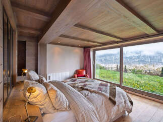 Experience luxurious mountain living in this stunning bedroom featuring a cozy bed with plaid bedding and a quilt, complemented by warm wood accents throughout.