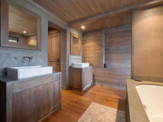 Experience rustic luxury in this stunning bathroom, featuring a spacious soaking tub and dual vanities with sleek vessel sinks.