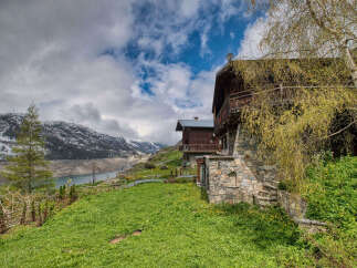 Nestled in a picturesque mountain landscape, this charming wooden chalet offers breathtaking views of a serene lake and snow-capped peaks.