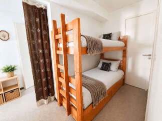This cozy bedroom features a sturdy wooden bunk bed, perfect for maximizing space in a vacation rental or children's room.