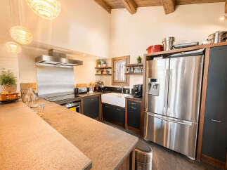 This spacious kitchen boasts a modern aesthetic with stainless steel appliances, including a large refrigerator and a sleek range hood over the stovetop.
