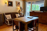 Experience cozy mountain living in this charming apartment, featuring a comfortable sofa and a rustic wooden dining table perfect for family meals.