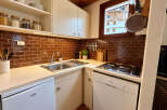 This compact kitchen boasts a sleek design with warm brown subway tile backsplash and ample counter space.