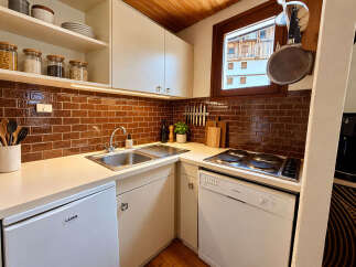 This compact kitchen boasts a sleek design with warm brown subway tile backsplash and ample counter space.