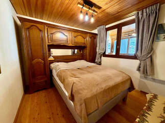 Experience cozy mountain living in this charming bedroom featuring a warm wooden ceiling and floor.