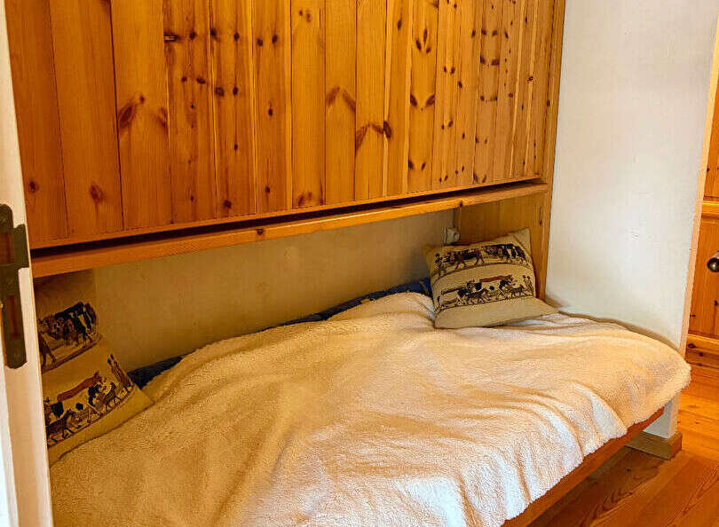 This cozy bedroom features a comfortable single bed with a plush white blanket, perfect for a relaxing retreat.