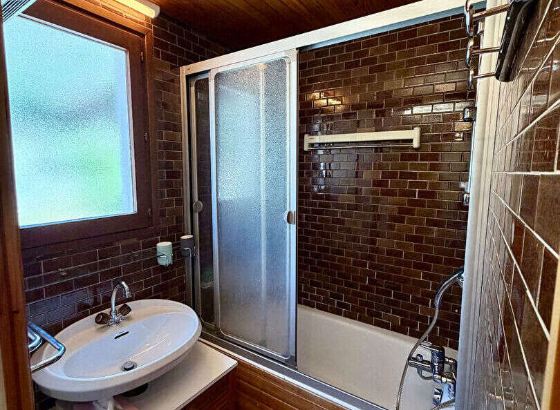 This charming bathroom features a sleek bathtub with a sliding glass door, perfect for a relaxing soak.