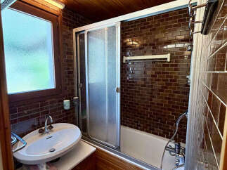 This charming bathroom features a sleek bathtub with a sliding glass door, perfect for a relaxing soak.