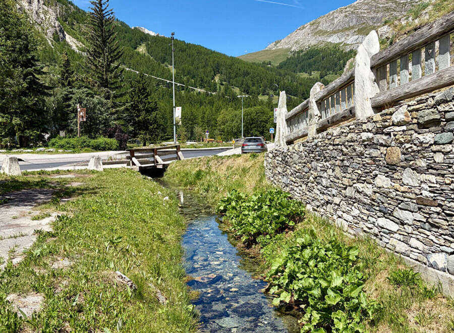 Discover this charming property nestled in a picturesque mountain setting, featuring a unique stone wall and rustic wooden bridge.