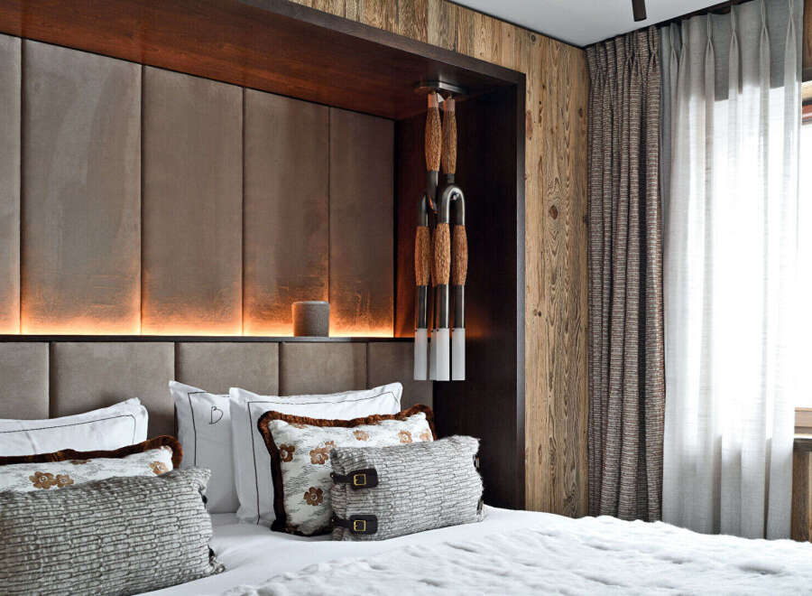 Experience rustic luxury in this master bedroom, featuring a plush upholstered headboard with integrated ambient lighting.