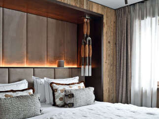 Experience rustic luxury in this master bedroom, featuring a plush upholstered headboard with integrated ambient lighting.