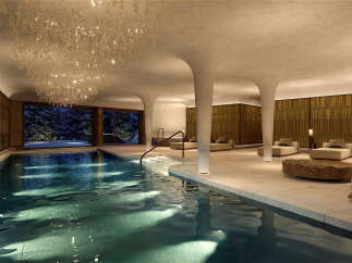 Indulge in luxury at this exquisite indoor swimming pool, featuring a stunning crystal chandelier and expansive windows overlooking a serene winter landscape.