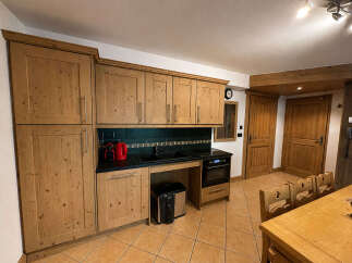 This charming kitchen features warm, natural wood cabinetry that extends from floor to ceiling, offering ample storage.