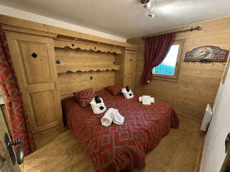 Experience cozy mountain living in this charming bedroom featuring a comfortable bed adorned with plush white robes and towels.