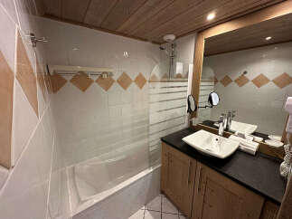 This charming bathroom features a spacious bathtub with a glass shower screen, perfect for relaxing after a long day.