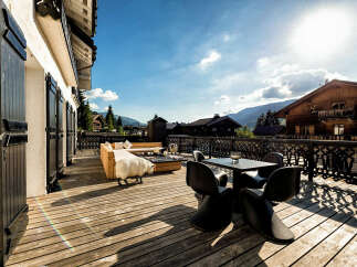 Experience luxury mountain living on this stunning wooden deck, complete with a modern outdoor dining set and a cozy lounge area.